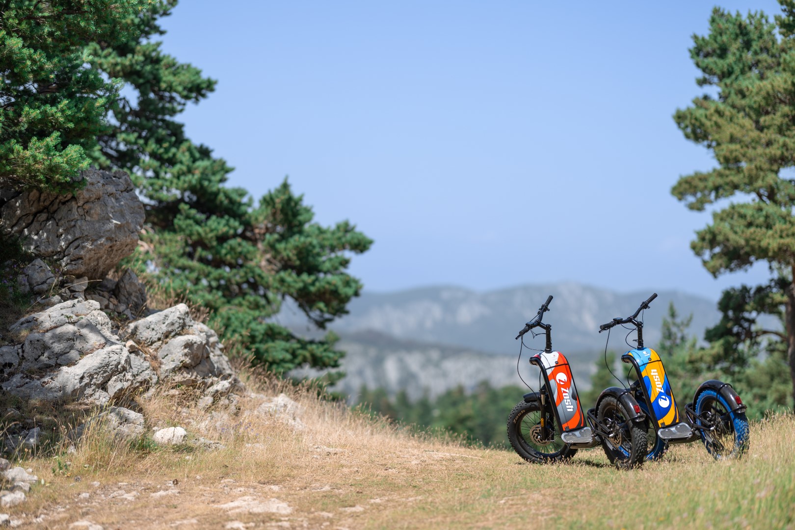 Deux trottinettes Zosh Mountain posées sur un plateau de garrigue face aux montagnes